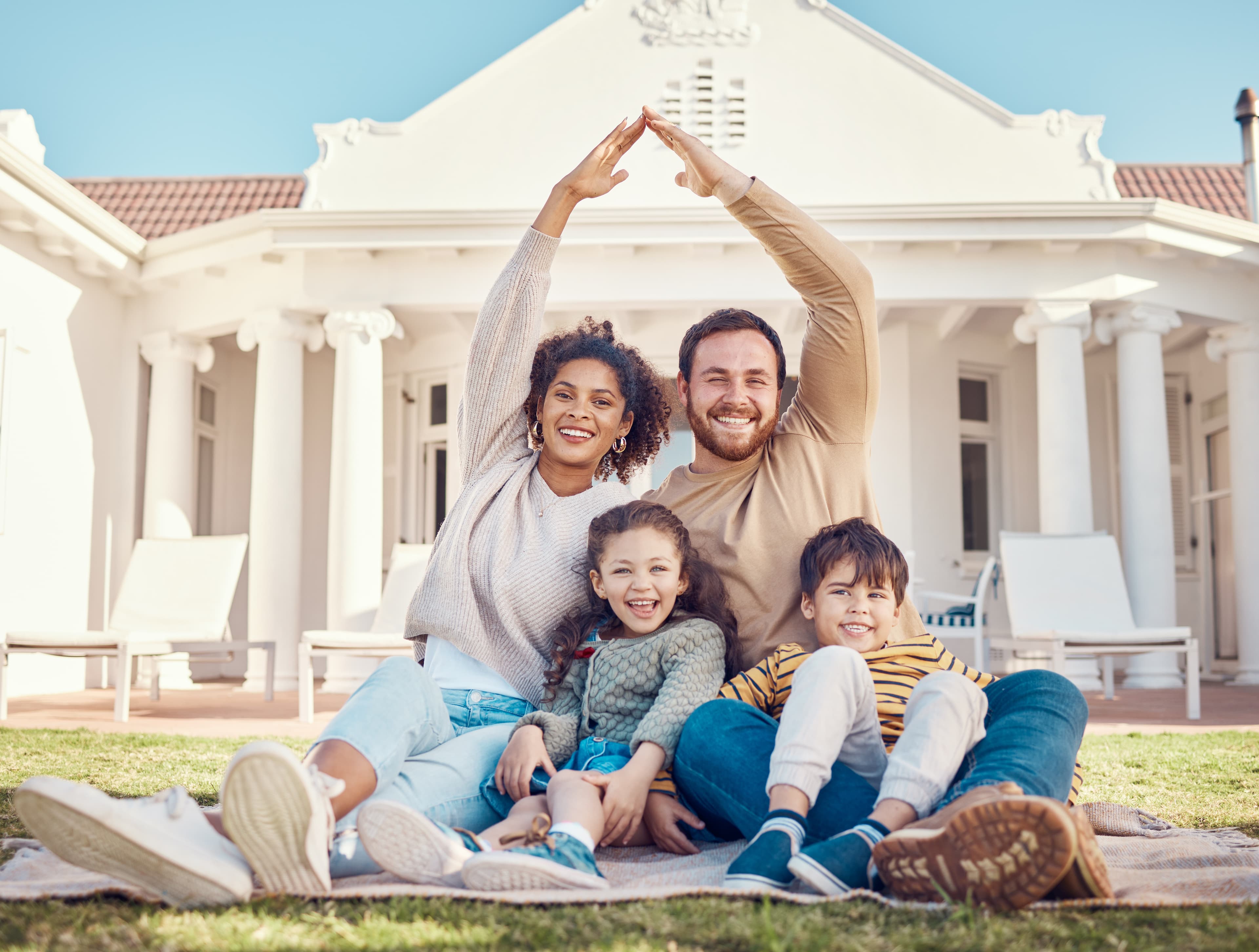 Family making a roof shape with their hands in front of their home